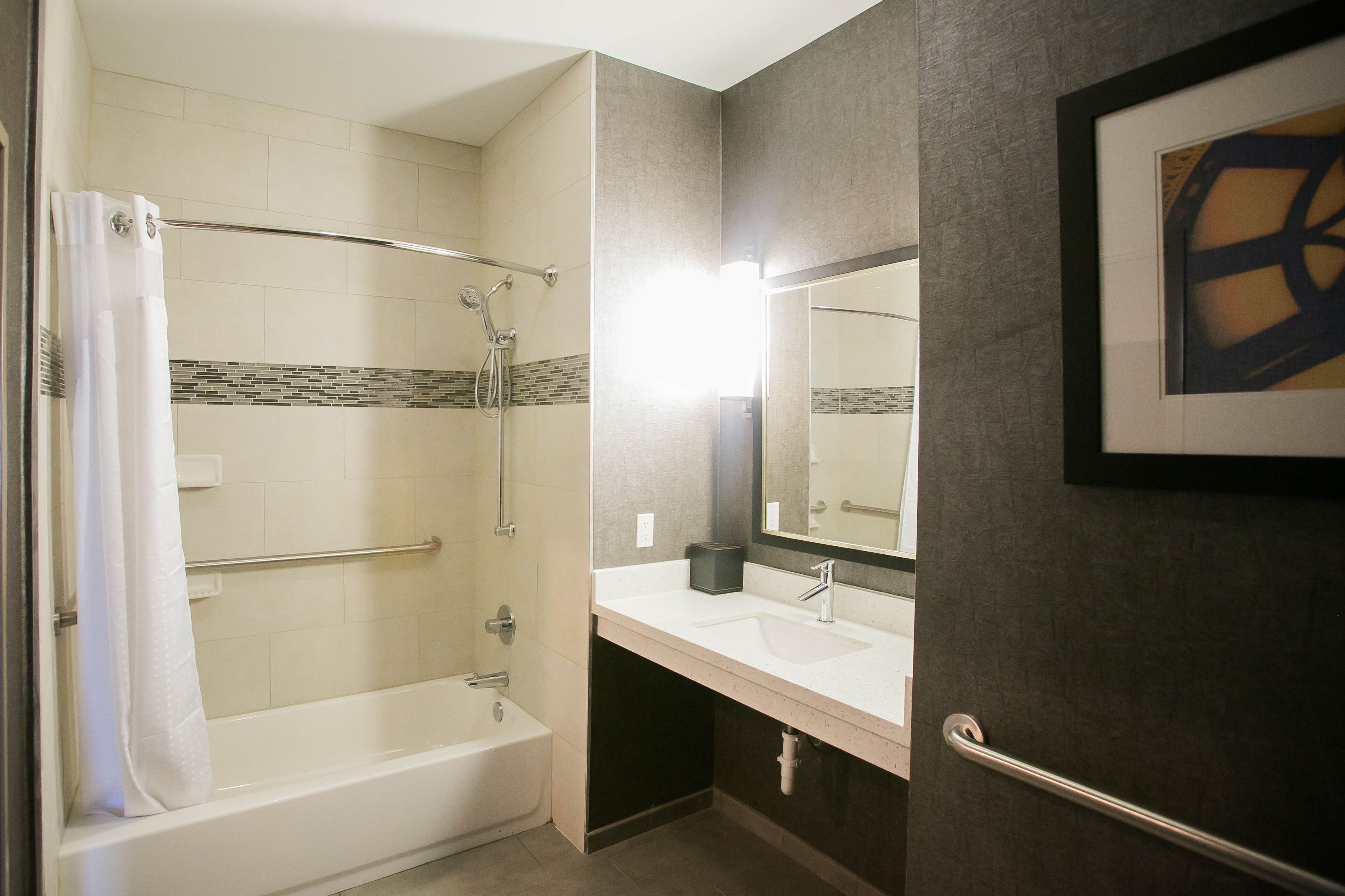 A modern bathroom with a bathtub, shower, and sink.