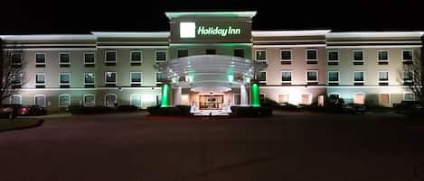 A Holiday Inn hotel with a prominent entrance, multiple floors, and a well-lit facade.