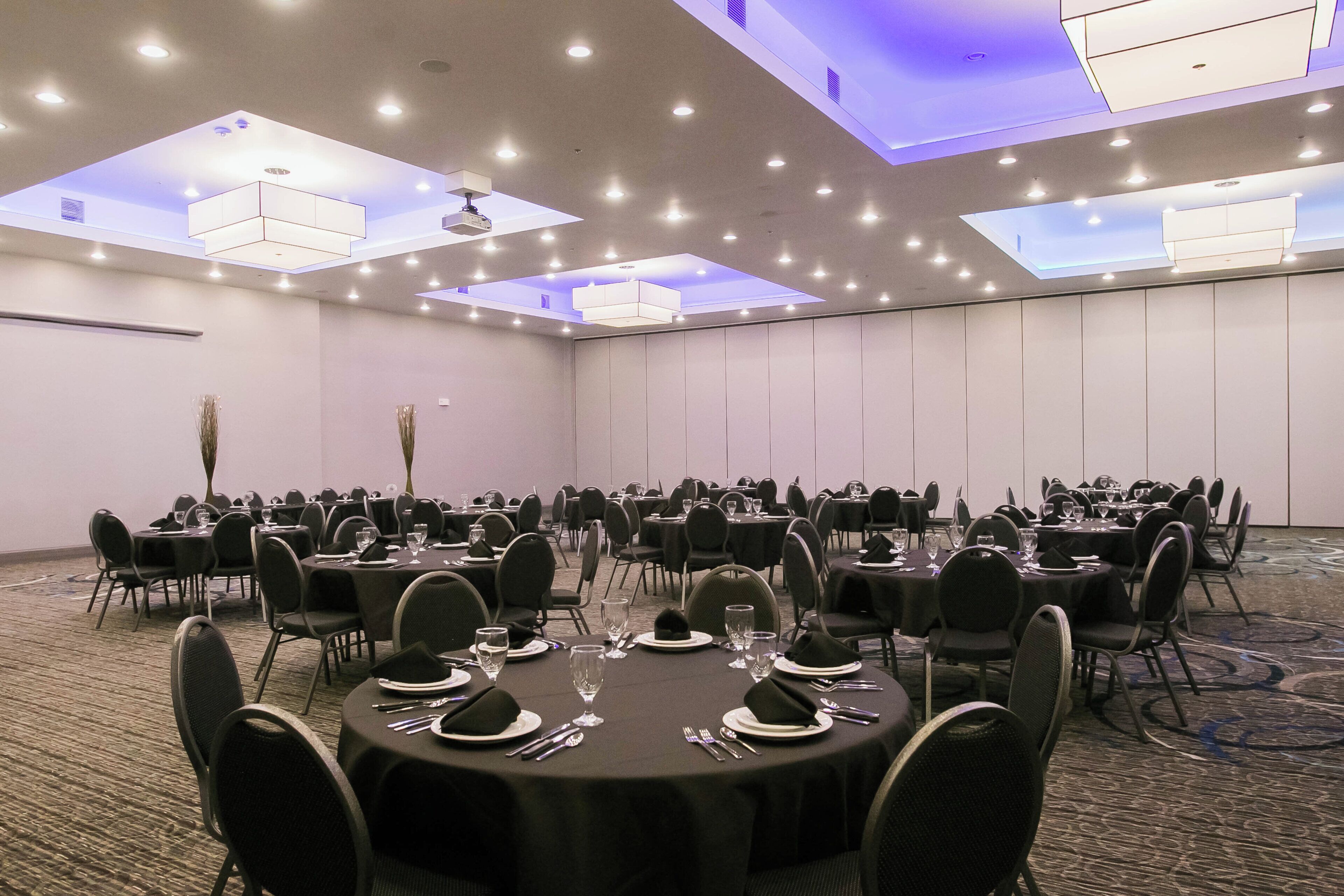 A conference room with multiple tables, chairs, and a carpeted floor.