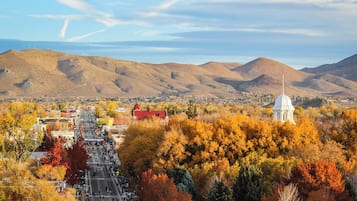 A town with a prominent white building, a red-roofed structure, and a street lined with autumn-colored trees.