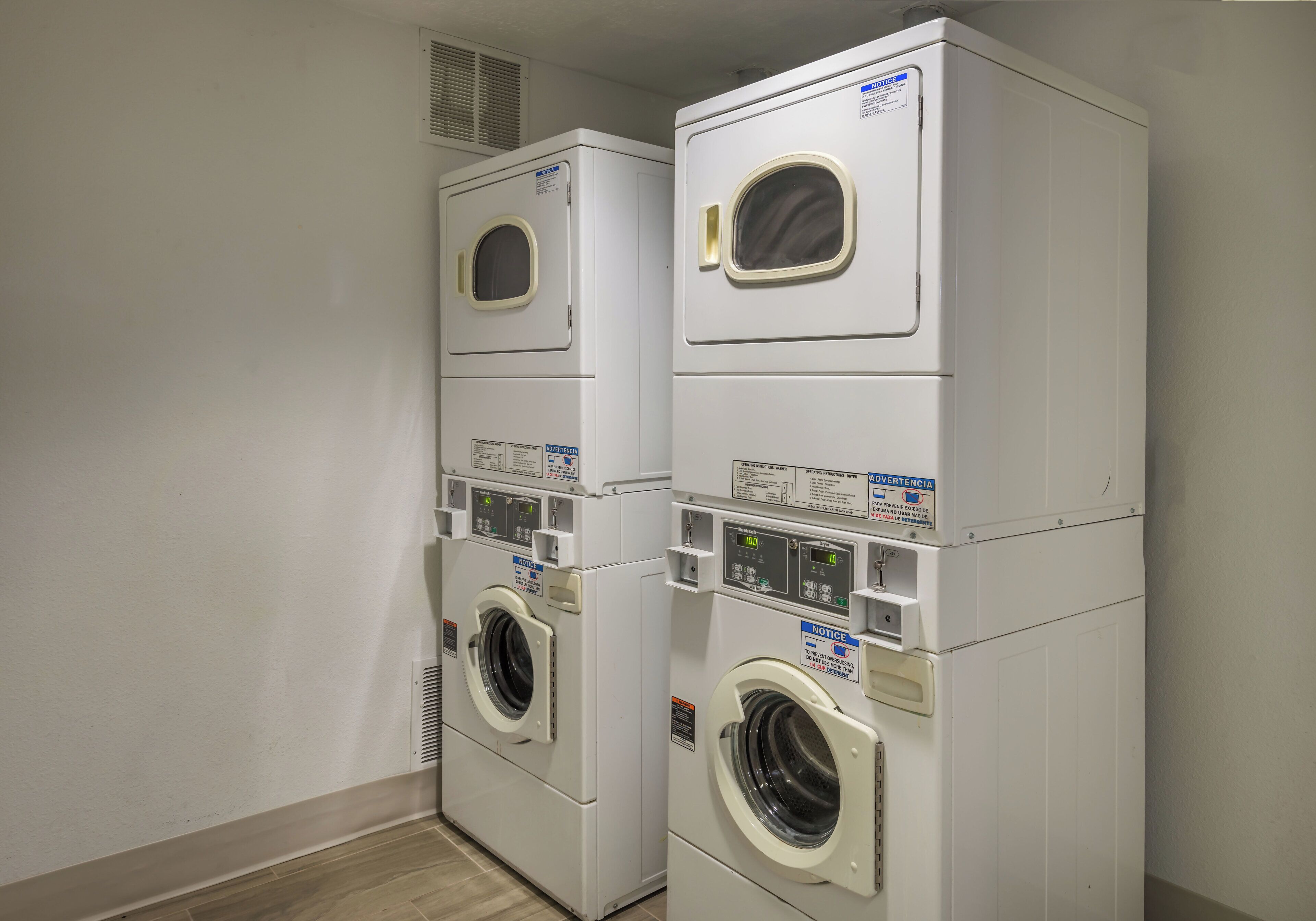 A laundry room with stacked front-loading washing machines and dryers.