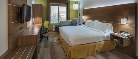 A hotel room with a bed, desk, chair, television, and a window with a view.