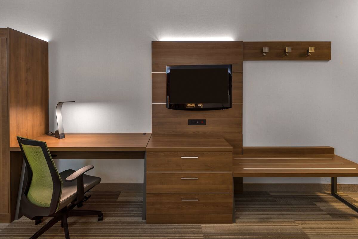 Un bureau moderne doté d’un téléviseur à écran plat, de tiroirs et d’une chaise.
