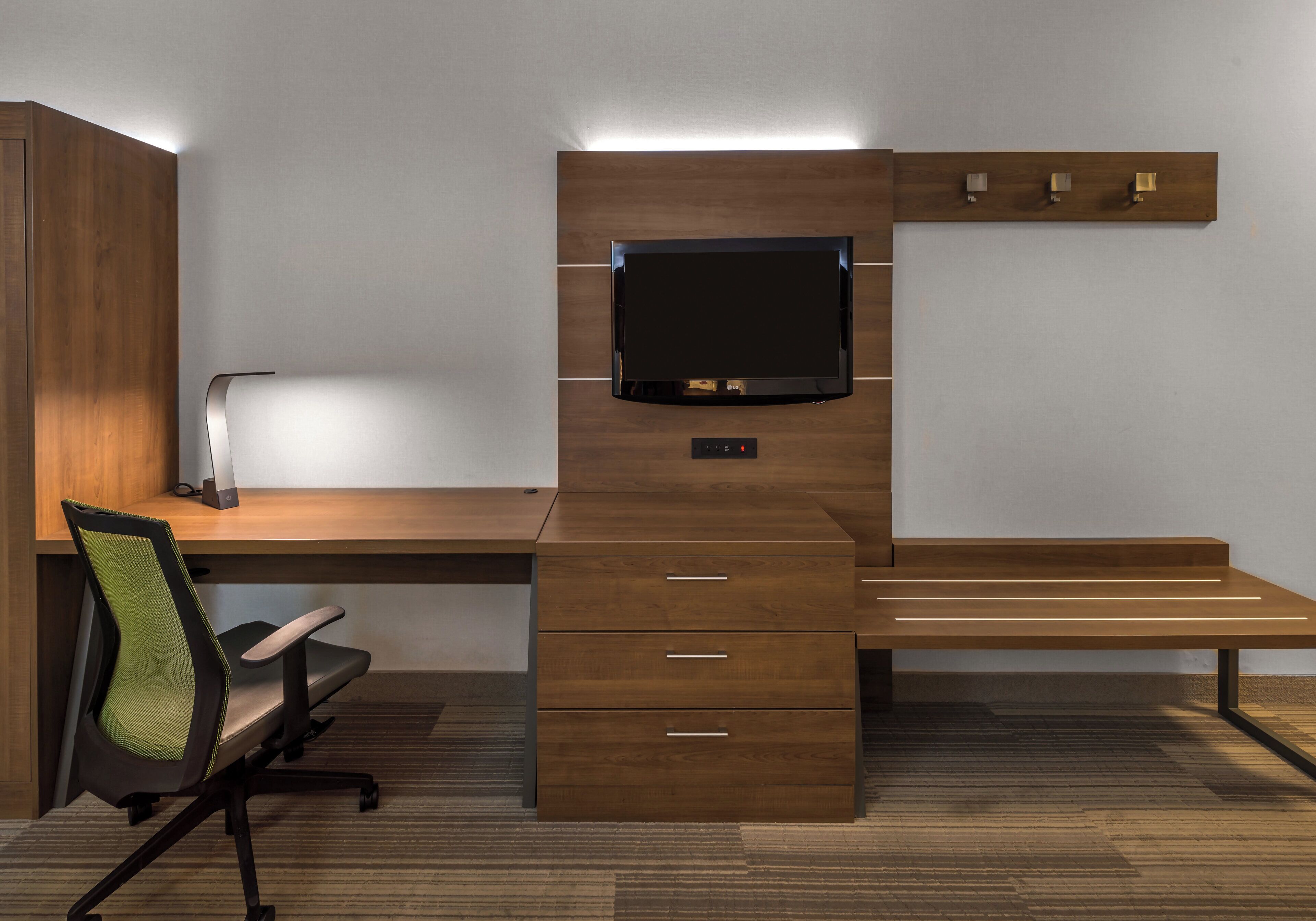 A modern office desk with a flat-screen monitor, drawers, and a chair.