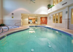 An indoor swimming pool with a clear water surface, a ceiling fan, and a door leading to a room with a view. - Holiday Inn Express & Suites Carson City by IHG (Carson City)