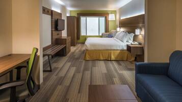 Habitació d'hotel amb un llit, escriptori, cadira, sofà, televisió i finestra.