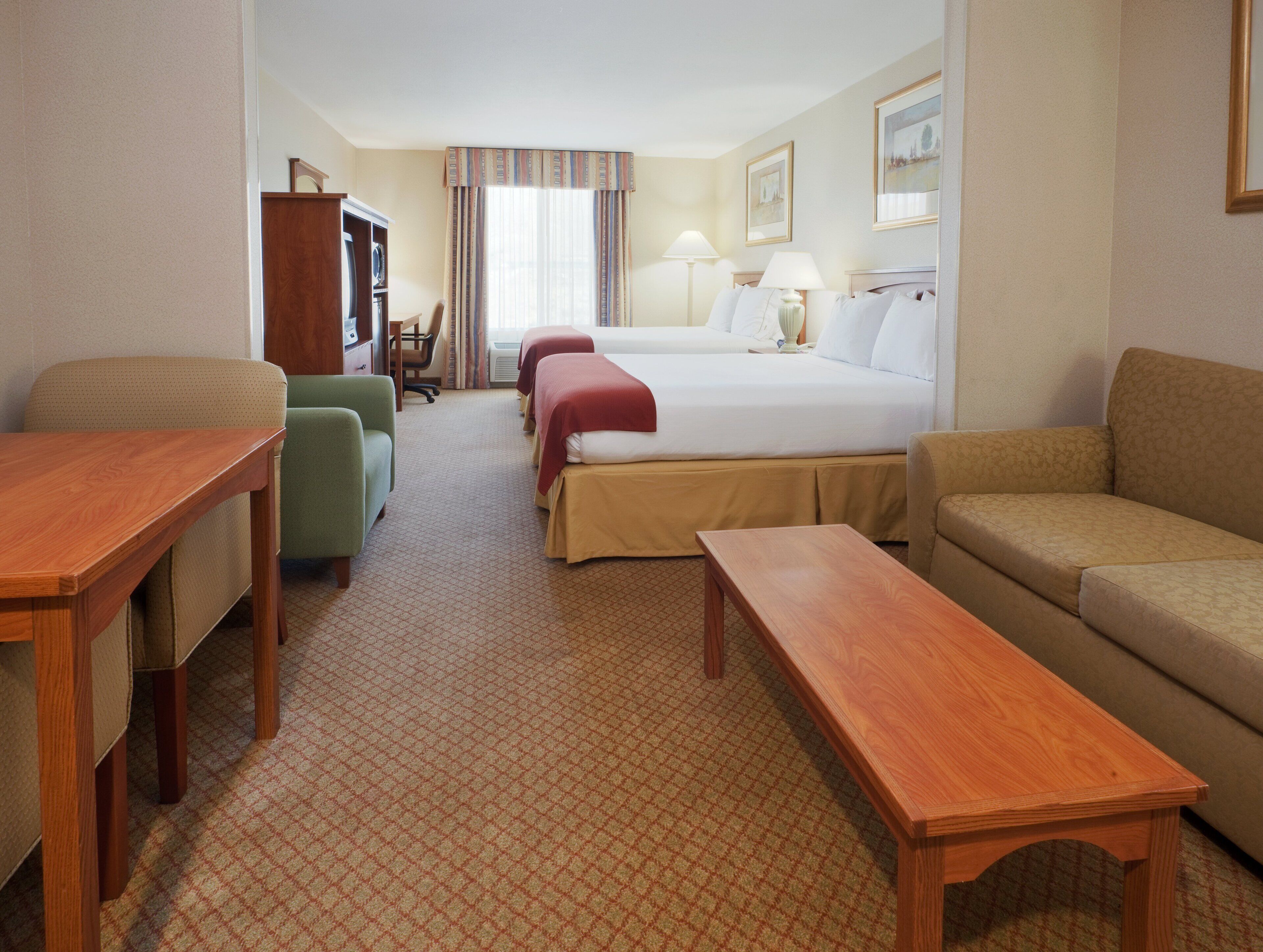Una habitación de hotel con una cama, dos mesitas de noche, un sofá, un escritorio y una silla.