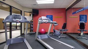 A gym with treadmills, a stationary bike, and a red exercise ball.
