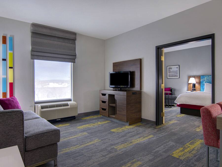 A hotel room with a bed, a TV, a desk, a chair, and a window with a view.
