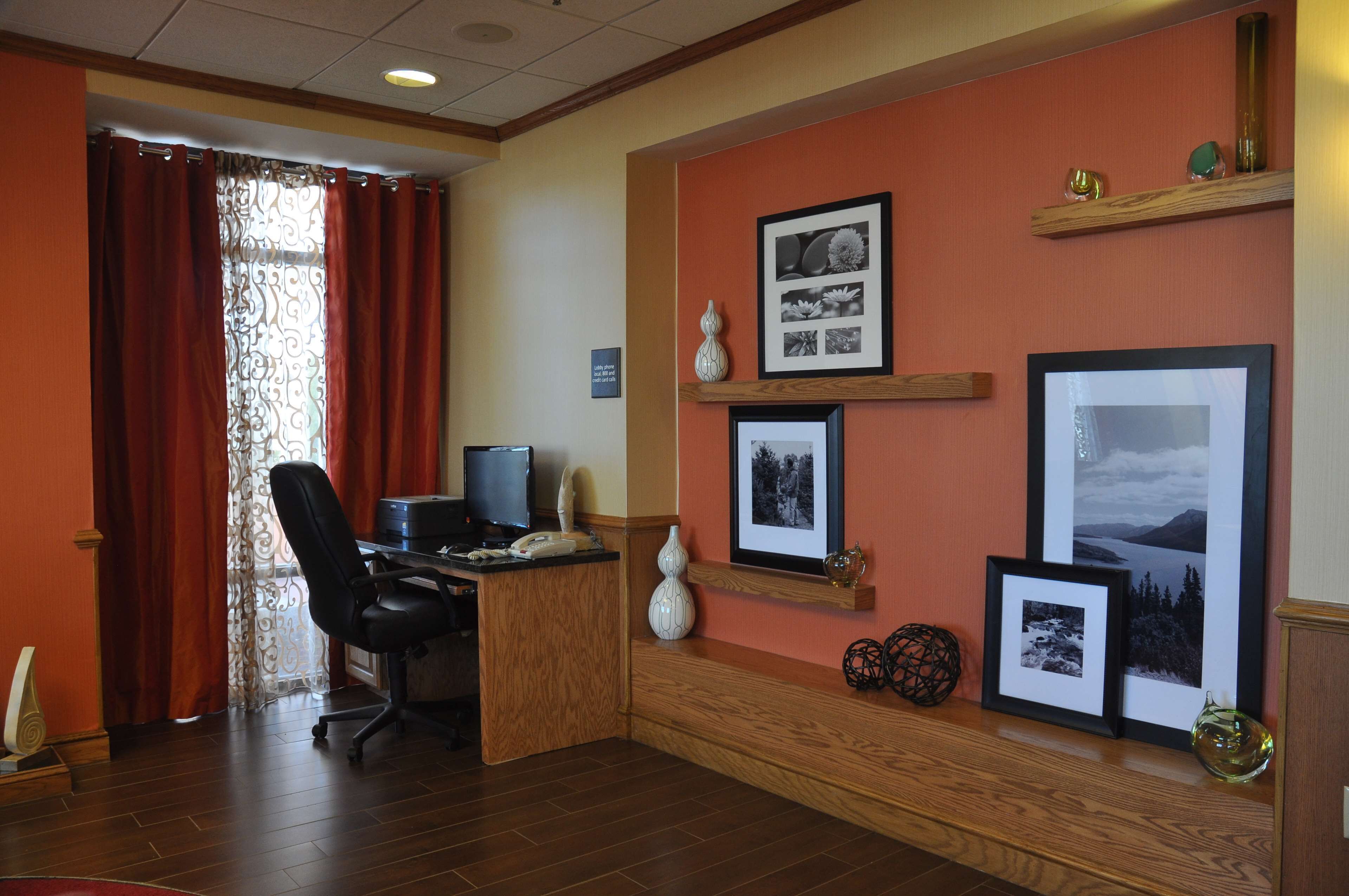 Habitación de hotel con escritorio, silla y un ventanal con cortinas.