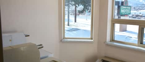 A room with a window overlooking a snowy landscape, a heater, and a sign for Cedar's Inn Motel.