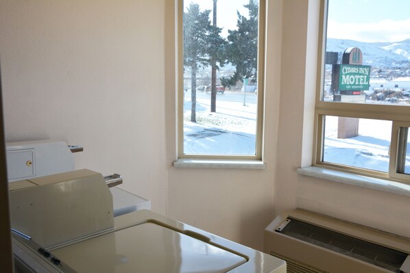 A room with a window overlooking a snowy landscape, a heater, and a sign for Cedar's Inn Motel.