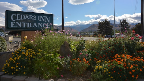 Señal de entrada a Cedar's Inn, con vistas a montañas y un estacionamiento al fondo.
