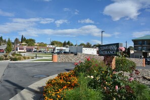 The entrance to Cedars Inn with a sign, a parking lot, and surrounding greenery.