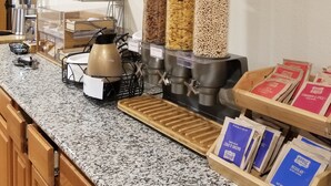 Una zona de cocina con cafetera, dispensadores de cereales y estación de café.
