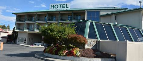 A hotel with a sign, a covered parking area, and a landscaped garden.