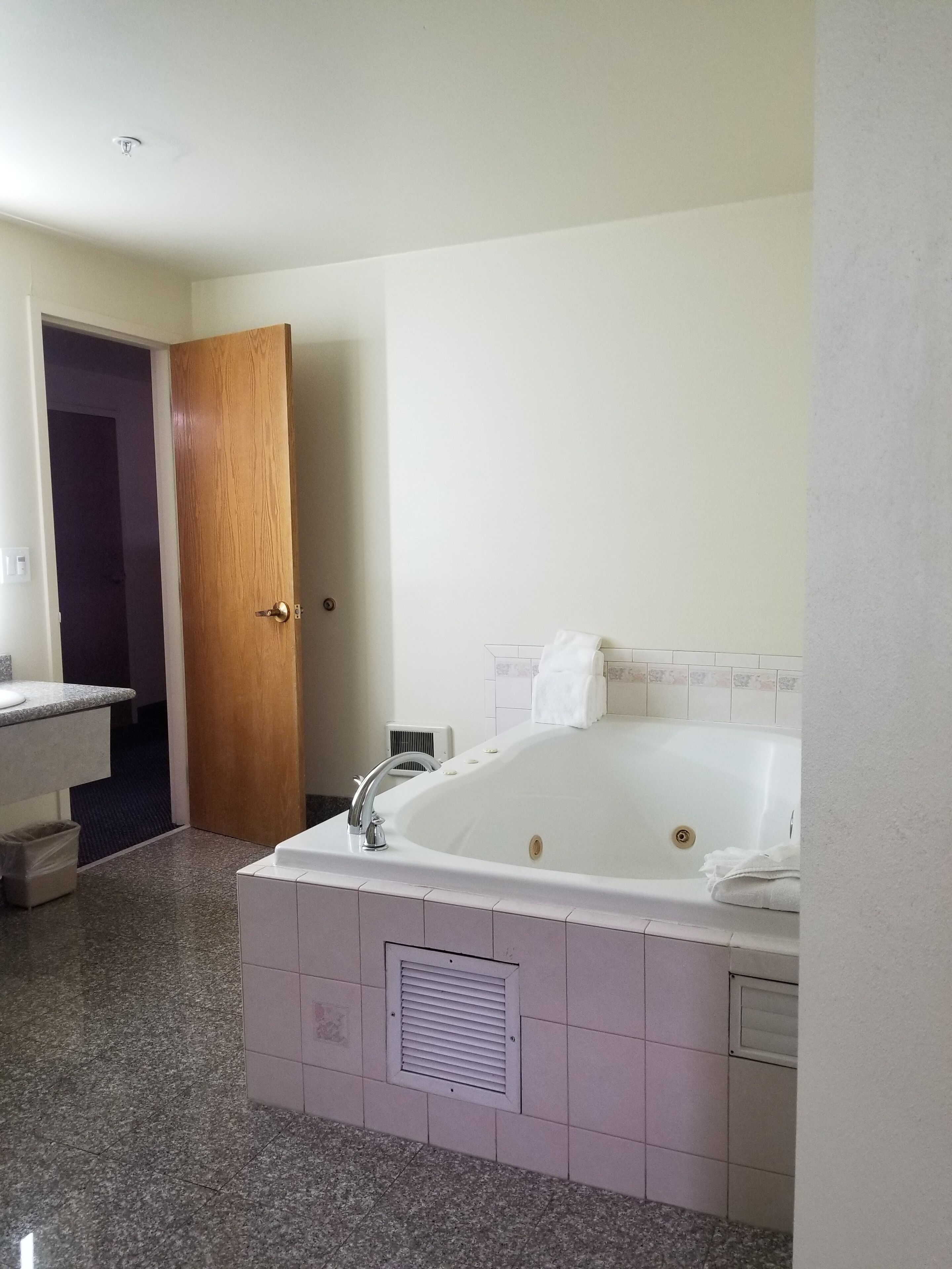 A bathroom with a large bathtub, a sink, and a door leading to another room.