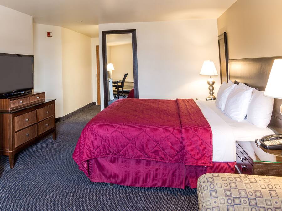 Ein Hotelzimmer mit einem großen Bett, einem Fernseher, einem Schreibtisch mit Lampe und einem Sessel.