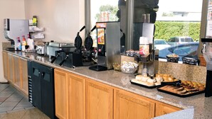 A kitchen area with a coffee machine, waffle maker, and various food items on the counter.
