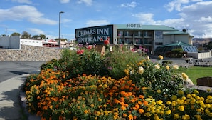 Entrada al Cedars Inn, con un letrero rodeada de un parterre con diversas flores.