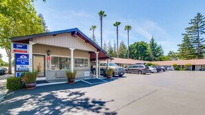 A motel with a covered front desk, parking area, and several parked cars. - Americas Best Value Inn Sky Ranch Palo Alto (Palo Alto)