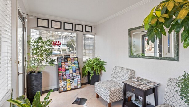 A well-lit room with a large window, a framed certificate on the wall, a seating area with a patterned chair, and a small table with magazines. - Americas Best Value Inn Sky Ranch Palo Alto (Palo Alto)