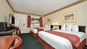Une chambre d’hôtel avec deux lits, un bureau avec une télévision, une porte et une fenêtre avec des rideaux.
