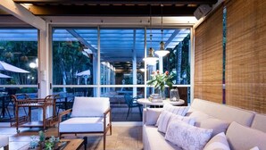 A modern interior with a sofa, chairs, and a coffee table. Large windows offer views of the outdoors. - Hotel Villa Morra Suites (Asunción)
