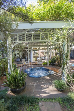 Un patio cubierto con jacuzzi, asientos y plantas en macetas.