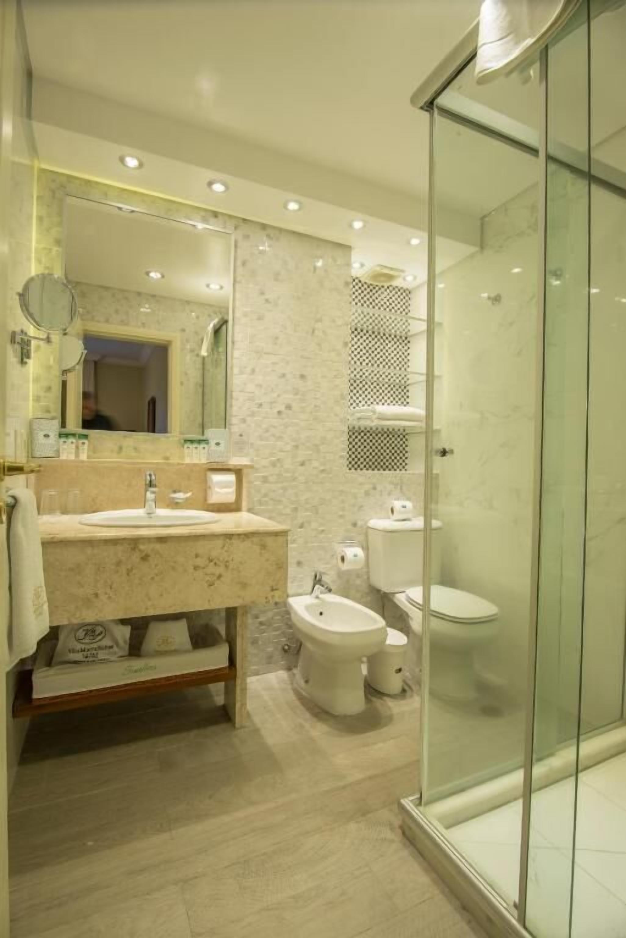 Un baño moderno con ducha de vidrio, lavamanos de mármol y bidé.