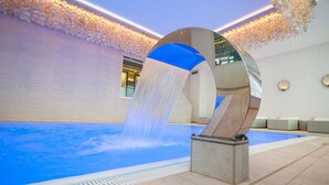 A modern indoor pool with a water feature and a decorative wall.