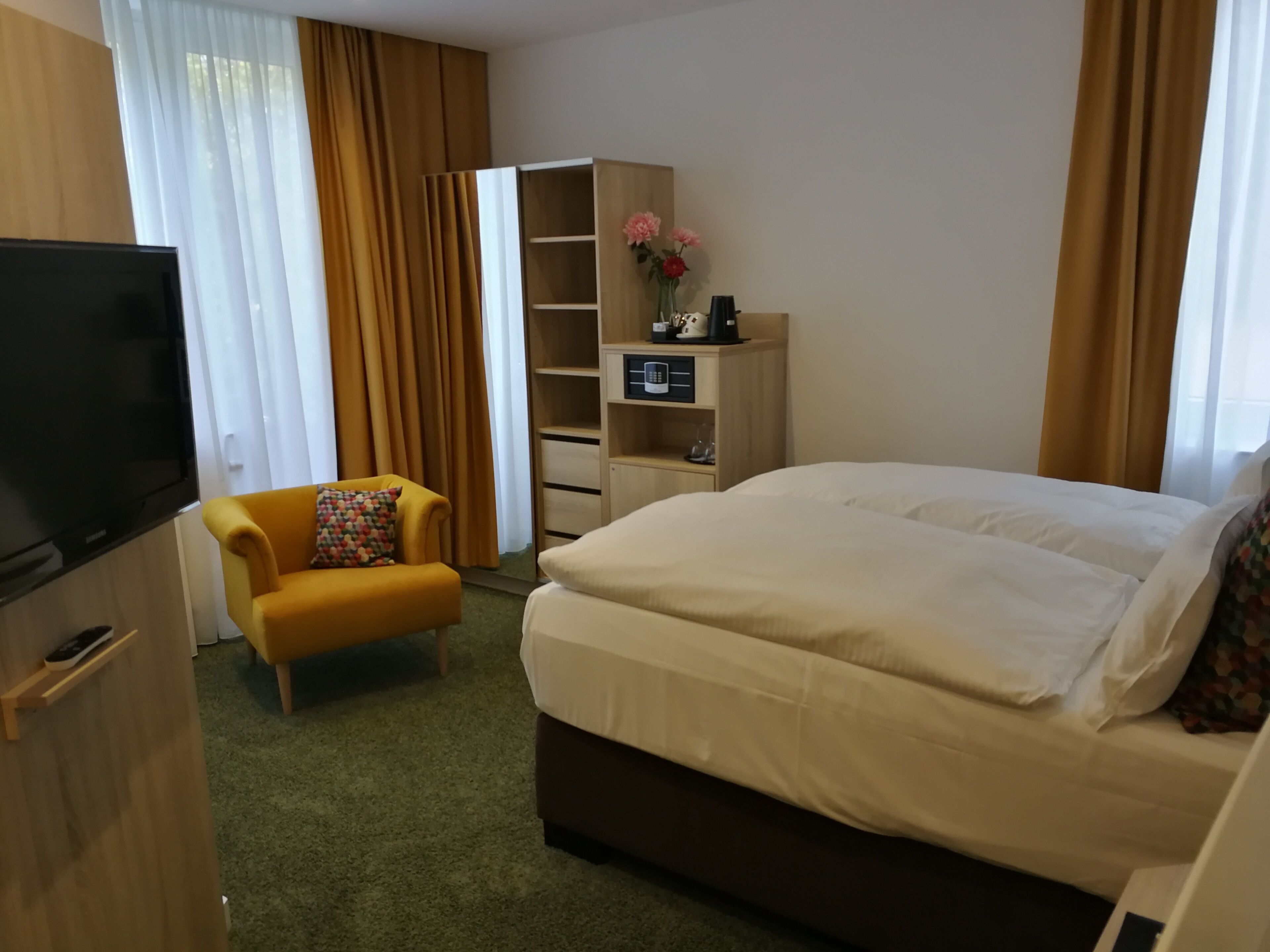 Een hotelkamer met een bed, een televisie, een sofa, een kledingkast en een bureau.