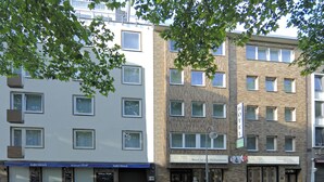 Een meerlaags hotel met een moderne gevel, bestaande uit baksteen en witte buitenmuren, grote ramen en een duidelijke ingang met een bord.