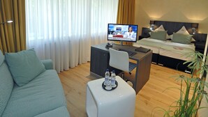 Hotelkamer met een bed, een televisie, een bureau, een stoel, een bank en een plant.
