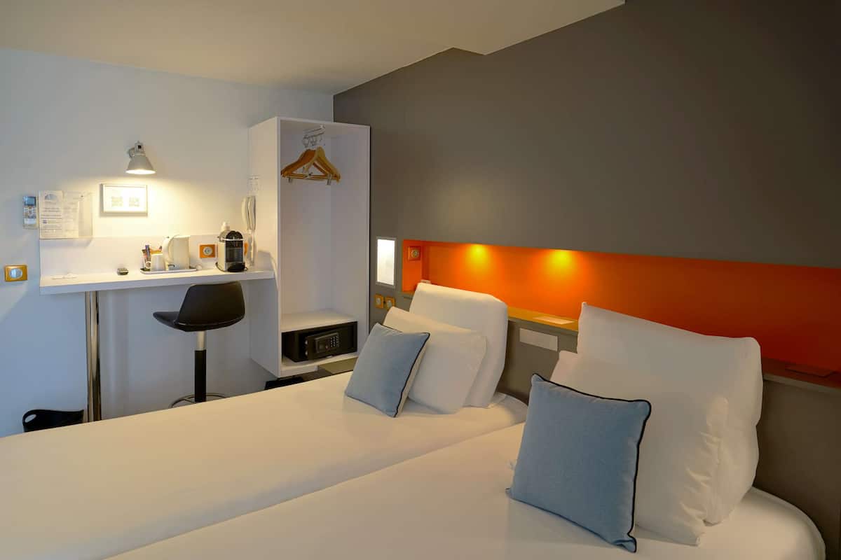 Ein Hotelzimmer mit Bett, Nachttisch, Stuhl, Schreibtisch und einer kleinen Ablagefläche.