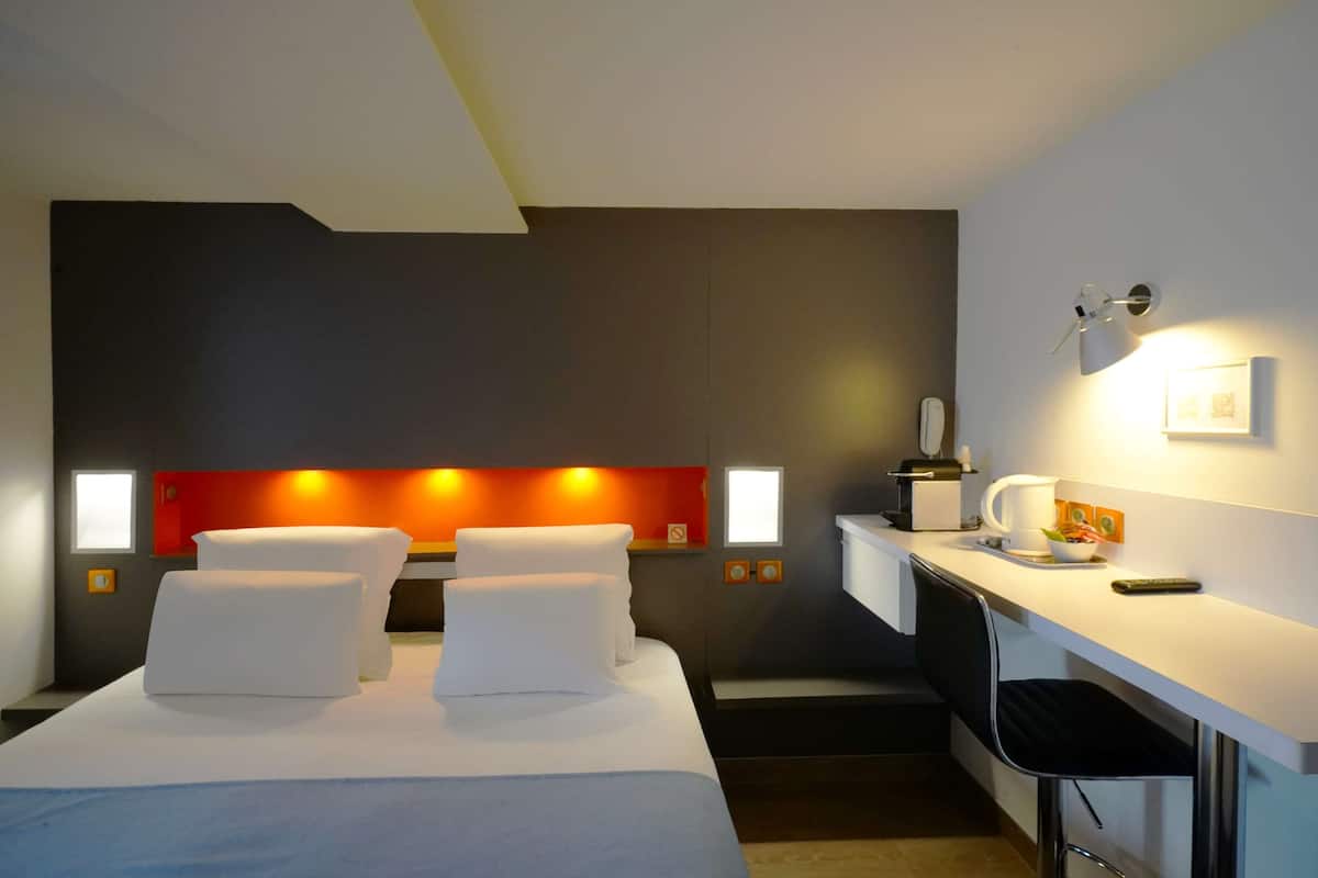 Ein Hotelzimmer mit Bett, Nachttischen, Schreibtisch und Stuhl.