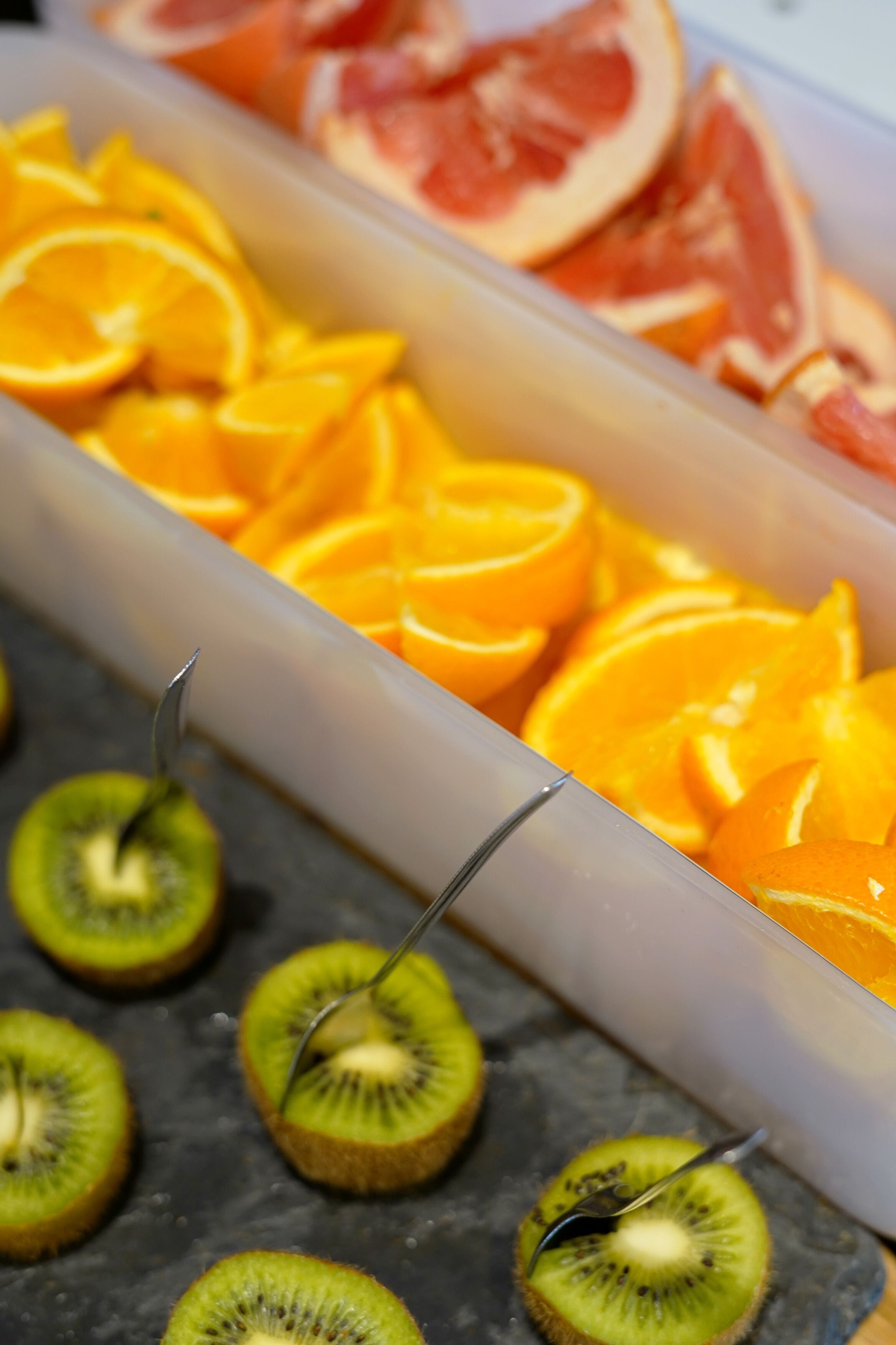 A container with sliced oranges and kiwis.