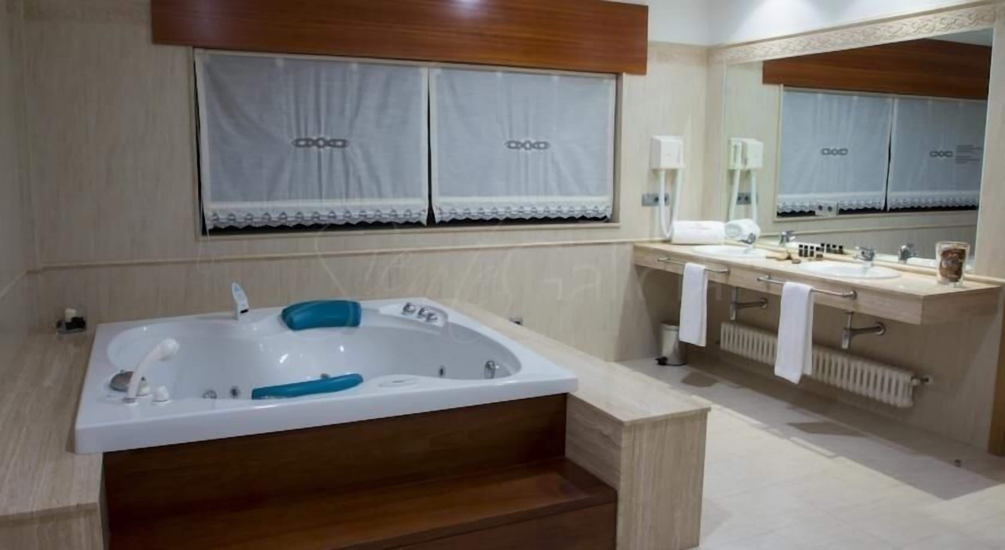 Een moderne badkamer met een ruime badkuip, een aparte douche en een wastafel met spiegel.