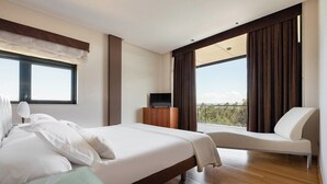 A modern hotel room with a large bed, a glass table, a sofa, and a TV. - Exe Via Argentum (Silleda)