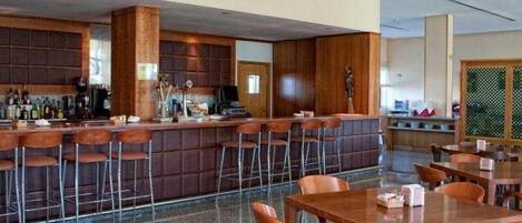 Un área de bar moderna con mostrador y taburetes, rodeada de paneles de madera y un suelo con diseño.