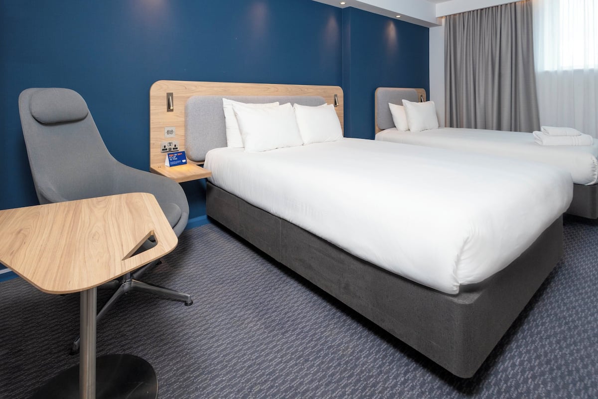 A hotel room with two beds, a desk, and a chair.