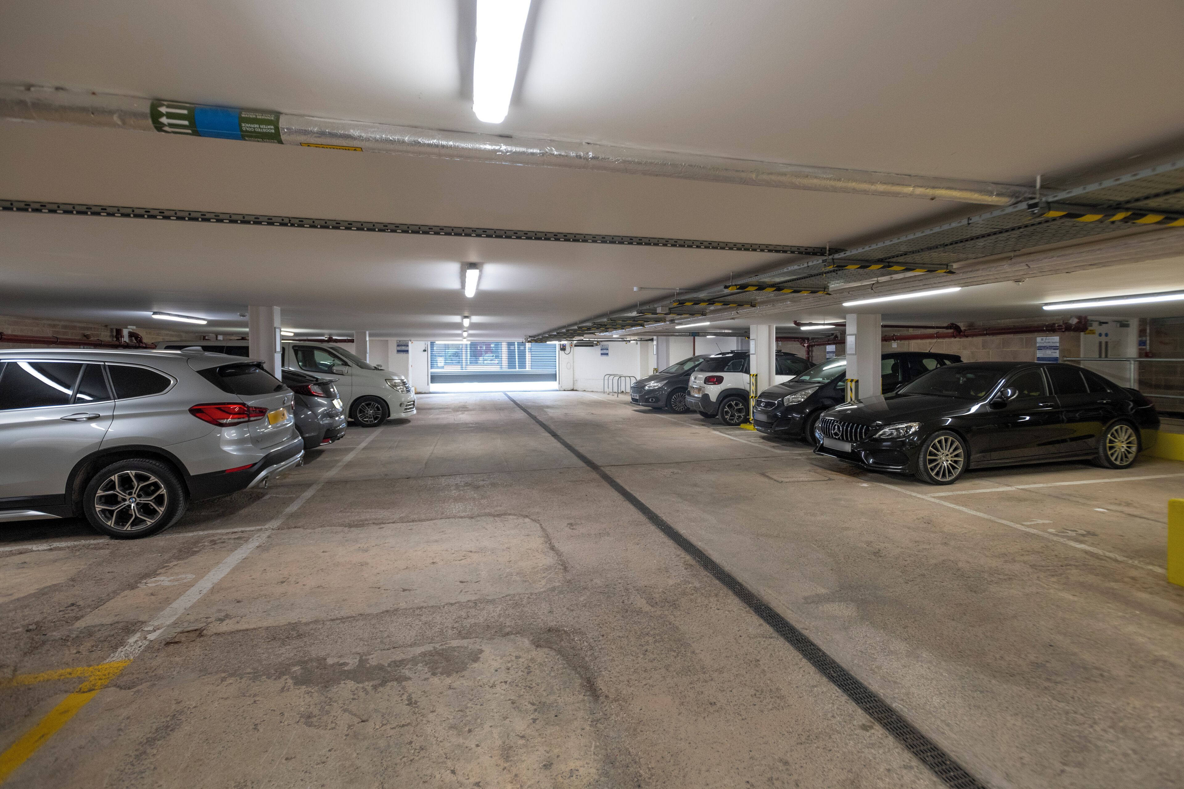 Un aparcamiento subterráneo de varios niveles con varios coches estacionados.