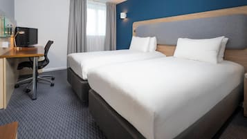A hotel room with two beds, a desk with a computer, and a chair.