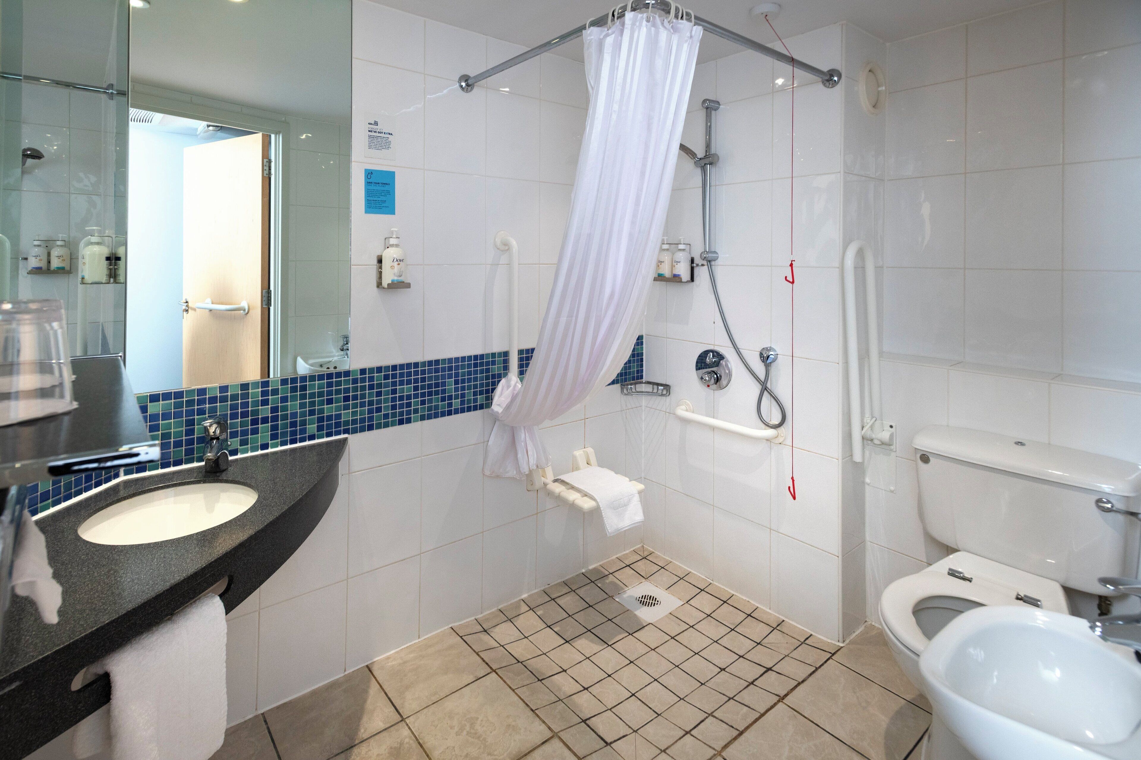 A bathroom with a sink, toilet, shower, and a glass-enclosed shower area.