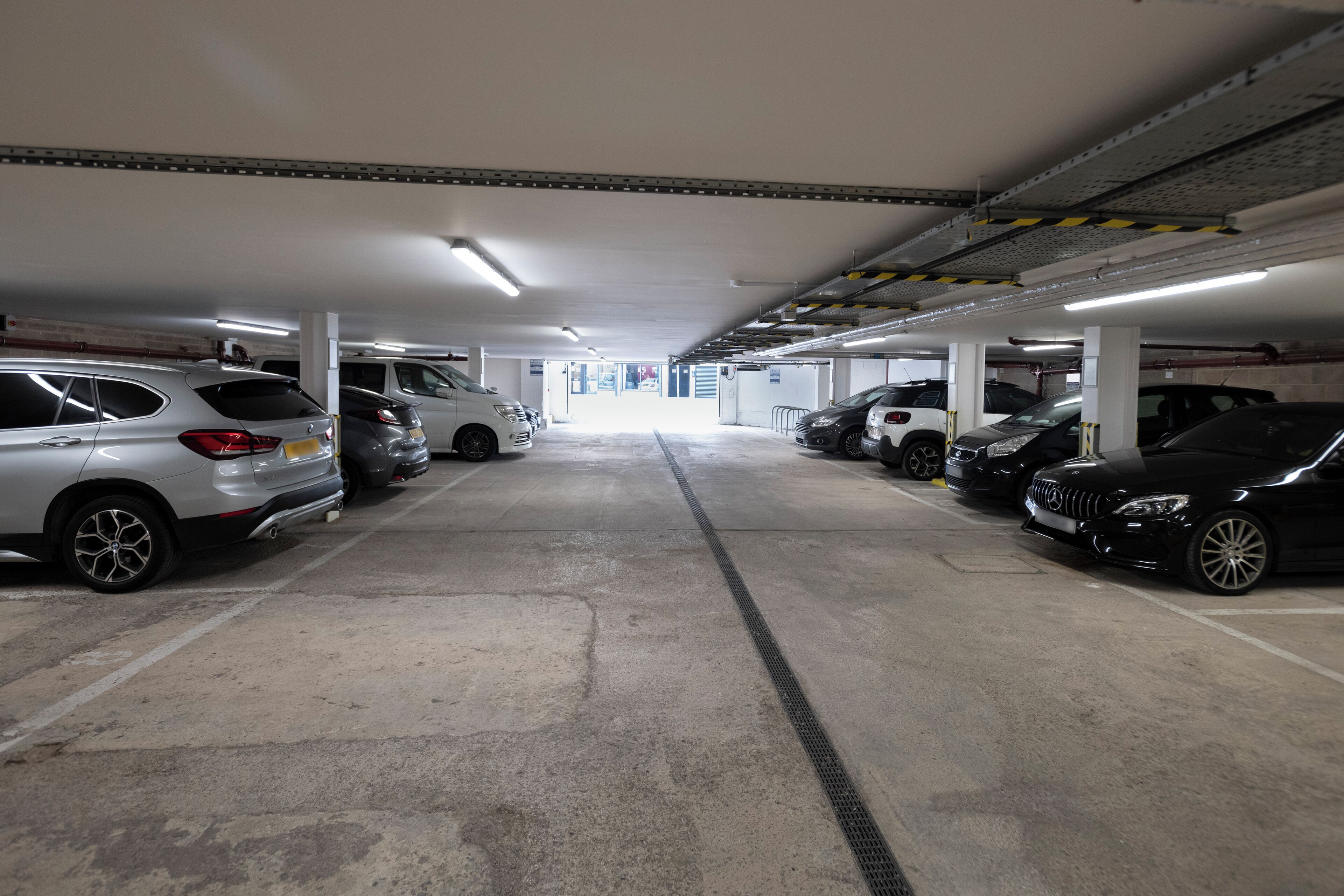 A multi-level underground parking garage with several cars parked in rows.