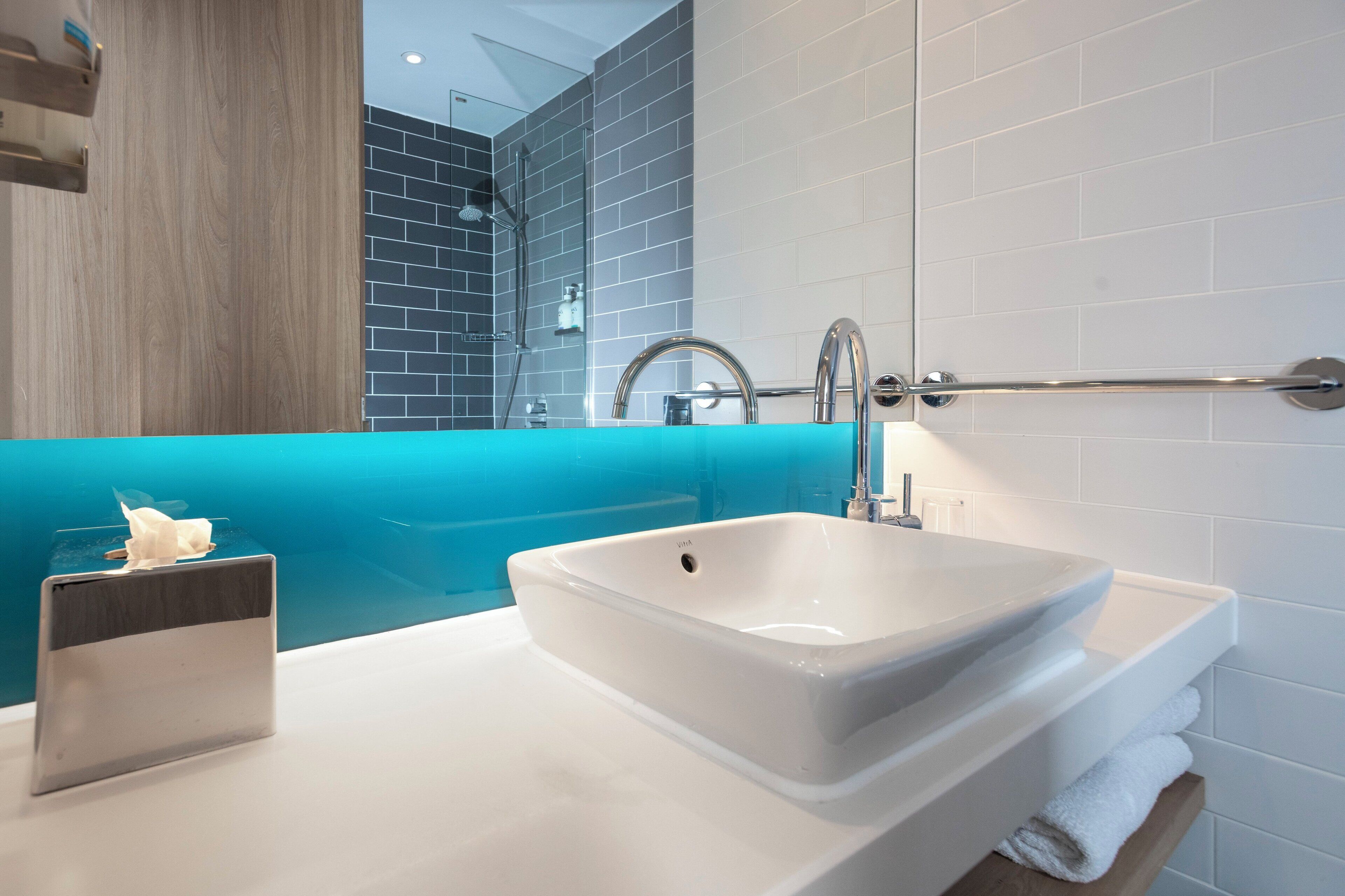 A bathroom with a white sink, a glass shower enclosure, and a wooden vanity.