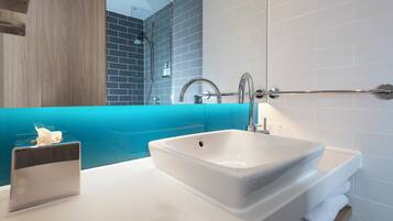 A bathroom with a white sink, a glass shower enclosure, and a wooden vanity.