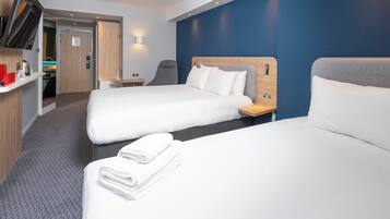 A hotel room with two beds, a desk, a chair, a TV, and a bathroom visible through an open door.