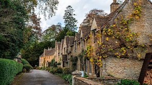 Une rangée de maisons en pierre aux toits très pentus, une rue étroite et une végétation luxuriante.