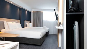 Una habitación de hotel con dos camas, un escritorio, un televisor y un baño.